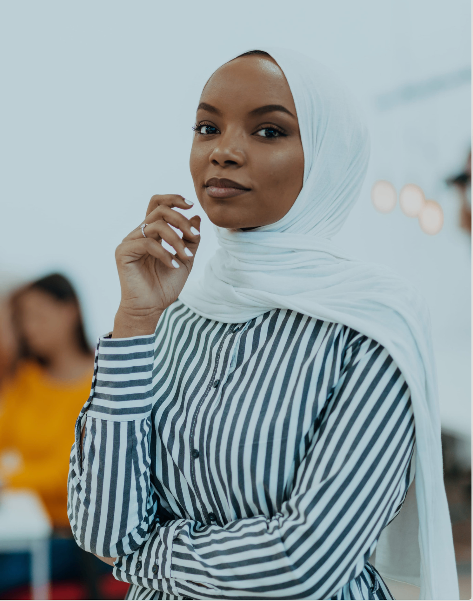 A woman in a white hijab and striped shirt in quiet reflection